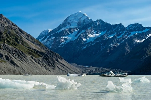 Icebergs float in a cold lake with a large snow covered mountain, South Island Icebergs float in a cold lake with a large snow covered mountain, South Island