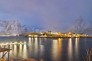 Illuminated Rorbu and houses in night fog during the cold winter, Sakrisoy, Reine, Nordland county, Lofoten Islands Illuminated Rorbu and houses in night fog during the cold winter, Sakrisoy, Reine, Nordland county, Lofoten Islands