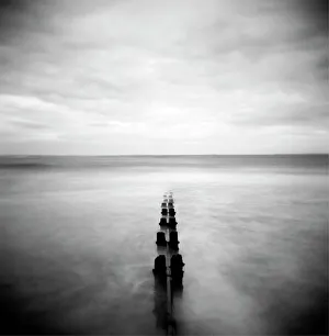 Image taken with a Holga medium format 120 film toy camera of view out to North Sea at dusk with sea washing around old wooden groynes, Alnmouth, Northumberland, England, United