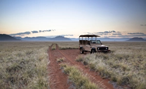 Land rover game vehicle parked by sand road at sunrise, Namib Rand game reserve Land rover game vehicle parked by sand road at sunrise, Namib Rand game reserve