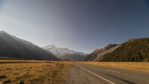 Late afternoon sun over a long straight road into the mountains, South Island, New Zealand Late afternoon sun over a long straight road into the mountains, South Island, New Zealand