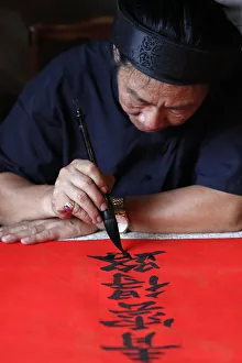 Man doing traditional Chinese writing (calligraphy) in ink using a brush Man doing traditional Chinese writing (calligraphy) in ink using a brush