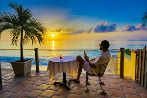 Man enjoying a beverage on a patio at sunset in Turks and Caicos Islands, Atlantic Man enjoying a beverage on a patio at sunset in Turks and Caicos Islands, Atlantic