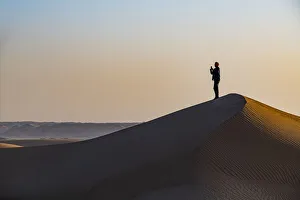 Man hiking through the sand dunes, Dirkou, Djado Plateau, Sahara, Niger, Africa Man hiking through the sand dunes, Dirkou, Djado Plateau, Sahara, Niger, Africa