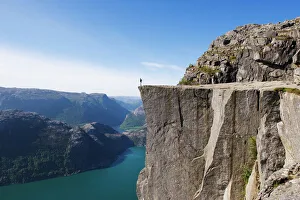 Man standing on Preikestolen (Pulpit Rock) above fjord, Lysefjord, Norway Man standing on Preikestolen (Pulpit Rock) above fjord, Lysefjord, Norway