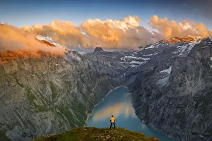 Man standing on rocks looking at clouds at sunset over lake Limmernsee, aerial view Man standing on rocks looking at clouds at sunset over lake Limmernsee, aerial view