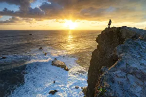 One man watching sunrise over the ocean waves from cliffs, Madeira island, Portugal One man watching sunrise over the ocean waves from cliffs, Madeira island, Portugal