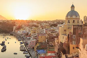 Marina Corricella at sunset, fishing village, colourful fishermens houses, boats and church Marina Corricella at sunset, fishing village, colourful fishermens houses, boats and church