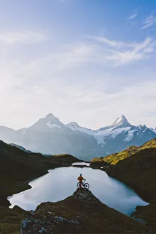 Mountain biker looking at Bachalpsee lake and Bernese Oberland mountains at dawn Mountain biker looking at Bachalpsee lake and Bernese Oberland mountains at dawn