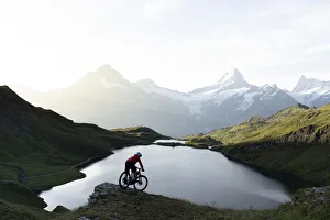 Mountain biker riding downhill at Bachalpsee lake at dawn, Grindelwald, Bernese Oberland Mountain biker riding downhill at Bachalpsee lake at dawn, Grindelwald, Bernese Oberland