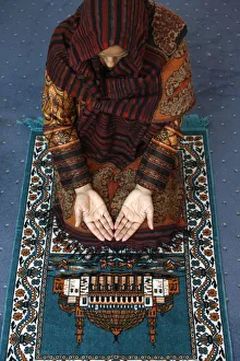 Muslim woman kneeling on prayer mat saying prayers, Jordan, Middle East Muslim woman kneeling on prayer mat saying prayers, Jordan, Middle East