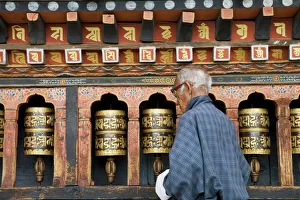 Old Bhutanese man turning prayer wheels in Buddhist temple, Thimphu, Bhutan, Asia Old Bhutanese man turning prayer wheels in Buddhist temple, Thimphu, Bhutan, Asia