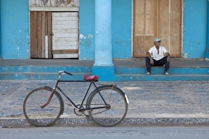 Old bicycle propped up outside old building with local man on steps, Vinales Old bicycle propped up outside old building with local man on steps, Vinales