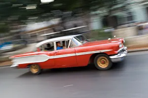 Old vintage American red and white car driving along a street in Havana, Cuba, West Old vintage American red and white car driving along a street in Havana, Cuba, West