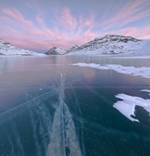 Panorama of the frozen Lago Bianco framed by pink clouds at dawn, Bernina Pass, canton Panorama of the frozen Lago Bianco framed by pink clouds at dawn, Bernina Pass, canton