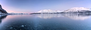 Panorama of pink sky and snowy peaks reflected in the frozen sea at sunset, Manndalen Panorama of pink sky and snowy peaks reflected in the frozen sea at sunset, Manndalen