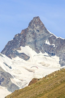 A paraglider flies in front of the majestic Obergabelhorn, Canton of Valais, Pennine Alps A paraglider flies in front of the majestic Obergabelhorn, Canton of Valais, Pennine Alps