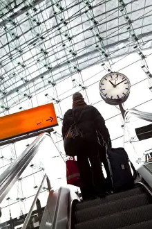 European Transportation Systems Prints: Passenger on escalator and platform clock at modern train station, Berlin