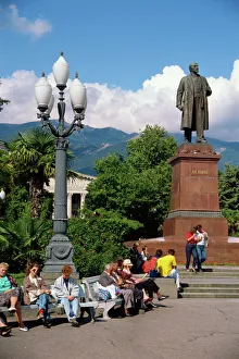 People sitting on benches near a statue of Lenin in Yalta People sitting on benches near a statue of Lenin in Yalta