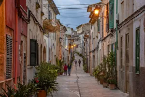 People in street in narrow street at dusk in the old town of Alcudia, Alcudia, Majorca, Balearic Islands, Spain People in street in narrow street at dusk in the old town of Alcudia, Alcudia, Majorca, Balearic Islands, Spain