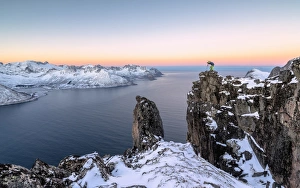 Photographer on the rocks on top of Mount Hesten admires the Mefjorden and the frozen Photographer on the rocks on top of Mount Hesten admires the Mefjorden and the frozen
