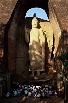 Pilgrims seated in front of the 39 ft high standing Buddha Pilgrims seated in front of the 39 ft high standing Buddha