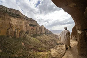 Rear view of priest walking on access trail to the rock-hewn Abuna Yemata Guh church Rear view of priest walking on access trail to the rock-hewn Abuna Yemata Guh church