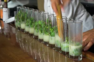 Row of glasses on a bar with barman preparing mojito cocktails, Habana Vieja Row of glasses on a bar with barman preparing mojito cocktails, Habana Vieja
