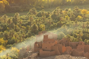 Ruined kasbah in the palmerie near Tinerhir, with smoke from fire swirling through the palm trees Ruined kasbah in the palmerie near Tinerhir, with smoke from fire swirling through the palm trees