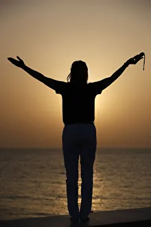 Silhouette of faithful woman praying with rosary beads at sunset as concept for religion Silhouette of faithful woman praying with rosary beads at sunset as concept for religion