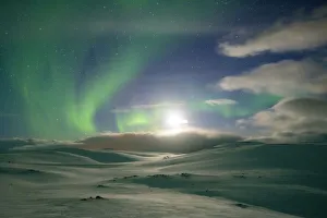 Snowy landscape lit by moon in the starry sky during the Northern Lights (Aurora Borealis Snowy landscape lit by moon in the starry sky during the Northern Lights (Aurora Borealis