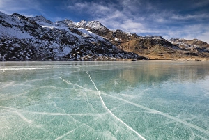 The snowy peaks frame the frozen turquoise water of White Lake (Lago Bianco), Bernina Pass The snowy peaks frame the frozen turquoise water of White Lake (Lago Bianco), Bernina Pass