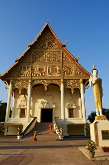 Statue of standing Buddha and monks, Pha That Luang temple, Vientiane, Laos Statue of standing Buddha and monks, Pha That Luang temple, Vientiane, Laos