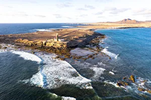 Sunset over the lighthouse of Punta Jandia (Faro de la Lola) washed by ocean waves Sunset over the lighthouse of Punta Jandia (Faro de la Lola) washed by ocean waves