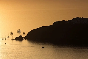 Sunset over the sea with boats and cliffs in silhouette near Oia, from Imerovigli Sunset over the sea with boats and cliffs in silhouette near Oia, from Imerovigli