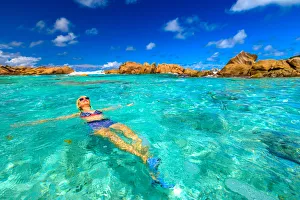 Swimming pool at Anse Cocos with woman in bikini lying in turquoise water of natural Swimming pool at Anse Cocos with woman in bikini lying in turquoise water of natural