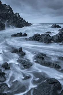 Swirling waves over dark rocks in a rugged North Devon cove, Devon, England, United Swirling waves over dark rocks in a rugged North Devon cove, Devon, England, United