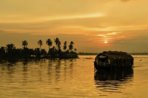 A traditional houseboat moves past the setting sun on the Kerala Backwaters, Kerala A traditional houseboat moves past the setting sun on the Kerala Backwaters, Kerala