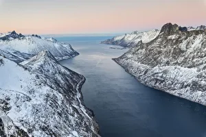 Top view of the snowy peaks surrounding Fjordgard framed by the frozen sea at sunset Top view of the snowy peaks surrounding Fjordgard framed by the frozen sea at sunset