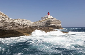 Waves of the turquoise sea crashing on the granite white cliffs and lighthouse Waves of the turquoise sea crashing on the granite white cliffs and lighthouse