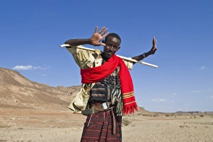 A young native man grinnig cheekily and holding a stick, Lac Abbe, Djibouti, Africa A young native man grinnig cheekily and holding a stick, Lac Abbe, Djibouti, Africa