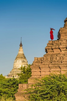 Bagan, Mandalay region, Myanmar (Burma). A young monk watching the Shwesandaw pagoda Bagan, Mandalay region, Myanmar (Burma). A young monk watching the Shwesandaw pagoda