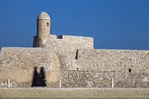 Bahrain, Manama, Women walking past Bahrain Fort - Qal'at al-Bahrain Bahrain, Manama, Women walking past Bahrain Fort - Qal'at al-Bahrain