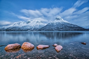 Blue sky at dusk and snowy peaks are reflected in the frozen sea at Oteren Storfjorden Blue sky at dusk and snowy peaks are reflected in the frozen sea at Oteren Storfjorden