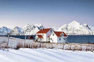 Blue sky on the wooden huts called Rorbu framed by frozen sea and snowy peaks Djupvik Blue sky on the wooden huts called Rorbu framed by frozen sea and snowy peaks Djupvik