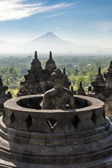Buddha statue with Mount Merapi in the background, Candi Borobudur buddhist temple Buddha statue with Mount Merapi in the background, Candi Borobudur buddhist temple