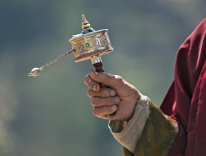 A Buddhist spins his hand-held prayer wheel in a clockwise direction with the help of a weighted chain attached to it A Buddhist spins his hand-held prayer wheel in a clockwise direction with the help of a weighted chain attached to it