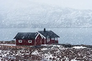 Two cabins along a fjord during a snowfall in the Lofoten islands, Norway Two cabins along a fjord during a snowfall in the Lofoten islands, Norway