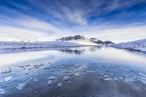 Mountain Pass Scenery Prints: Clouds is reflected in the icy surface of alpine lake. Stelvio pass, Valtellina, Lombardy
