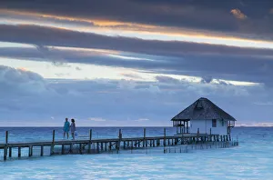 Couple on jetty at sunset, Fakarava, Tuamotu Islands, French Polynesia Couple on jetty at sunset, Fakarava, Tuamotu Islands, French Polynesia